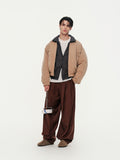Person wearing a beige jacket with plaid shirt and brown pants on a white background